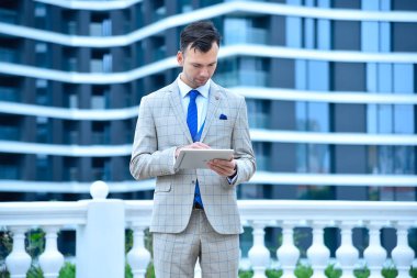 Trader man hands using digital tablet computer with stock data on a modern skyscraper background. Business and information technology concept. Close up