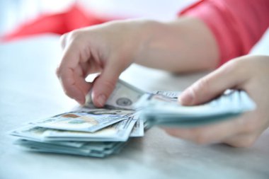 Woman counting dollars banknotes at table in modern office. Financial success and business concept. Close up
