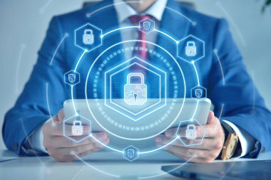 Businessman holding tablet computer and digital lock icon hologram with digital shield. Cyber security and digital protection concept.