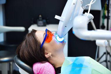 Modern dişçi kliniğinde diş beyazlatma. Klinikte diş beyazlatıcı lazer. Hasta için diş beyazlatma. Kapat.