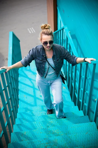 Cool girl climbs the ladder of turquoise color — Stock Photo, Image