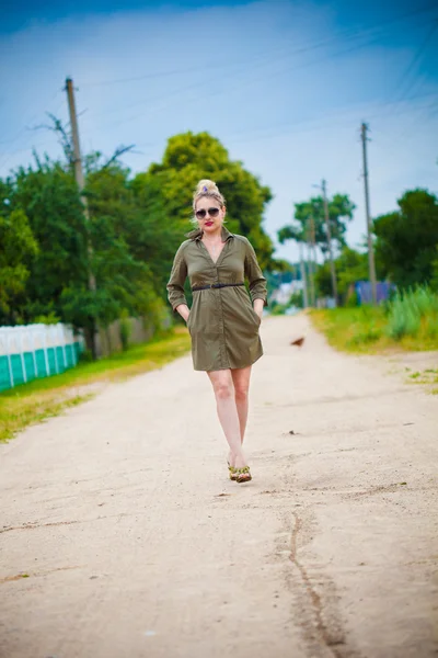 Menina bonita andando em uma estrada rural em vestido verde — Fotografia de Stock