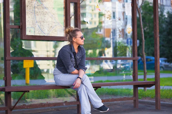 Chica solitaria esperando el transporte en la parada de autobús — Foto de Stock