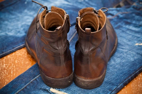 Lederen schoenen bruine en blauwe jeans. modieuze lederen hoge laarzen. — Stockfoto