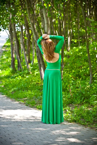 Krásná dívka s vlasy v zelených šatech s pruh na zádech — Stock fotografie