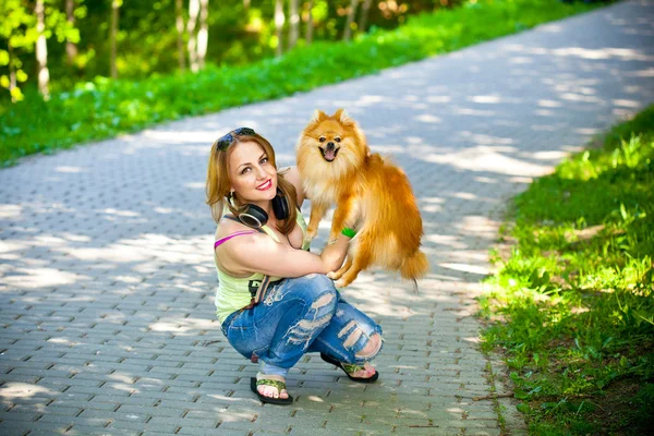 Mooi meisje in shirt en spijkerbroek buiten met haar hond spitz — Stockfoto