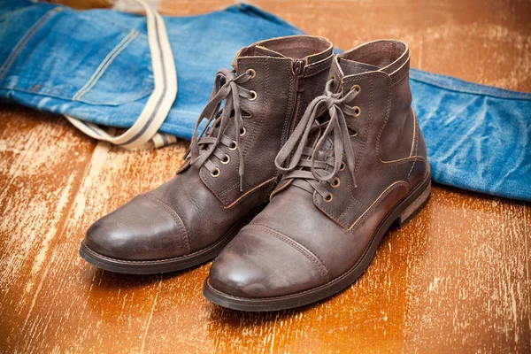 Lederen schoenen bruine en blauwe jeans. modieuze lederen hoge laarzen. — Stockfoto