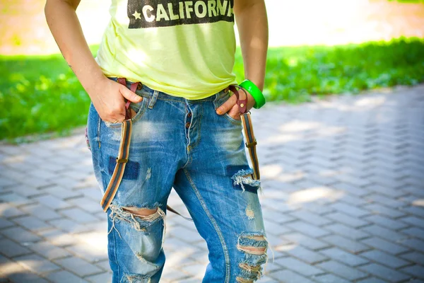 Closeup girl in T-shirt and jeans with suspenders — Stock Photo, Image