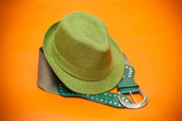 Зеленая шляпа и зеленый пояс с пряжкой в западном стиле на оранжевом фоне — стоковое фото