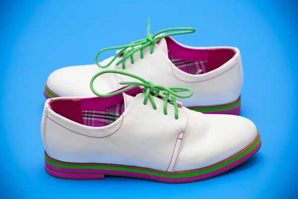Chaussures blanches avec lacets verts sur fond bleu — Photo