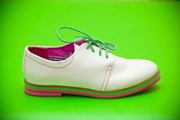 Chaussures blanches avec lacets verts sur fond vert — Photo