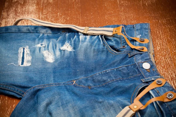 Pantalones vaqueros azules gastados con agujeros y tirantes —  Fotos de Stock