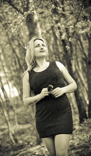 Retrato de una hermosa niña en la naturaleza, en el bosque, en un vestido negro. Sepia foto tonificada —  Fotos de Stock