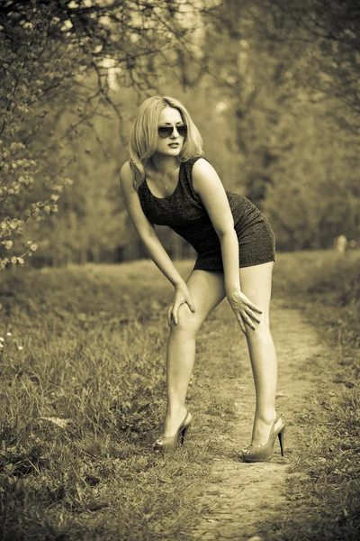 Menina sexy em um vestido e sapatos na floresta. Sepia foto tonificada — Fotografia de Stock