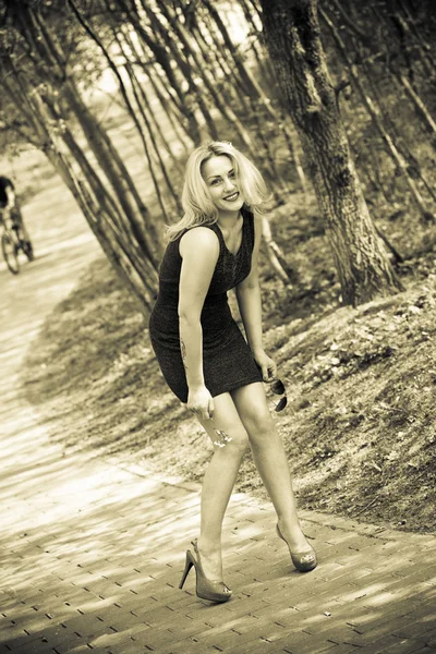 Ritratto di una bella ragazza sorridente in natura. ragazza sexy in un vestito e scarpe nella foresta. Seppia foto tonica — Foto Stock