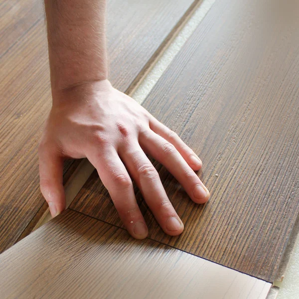 Homem que estabelece piso laminado — Fotografia de Stock