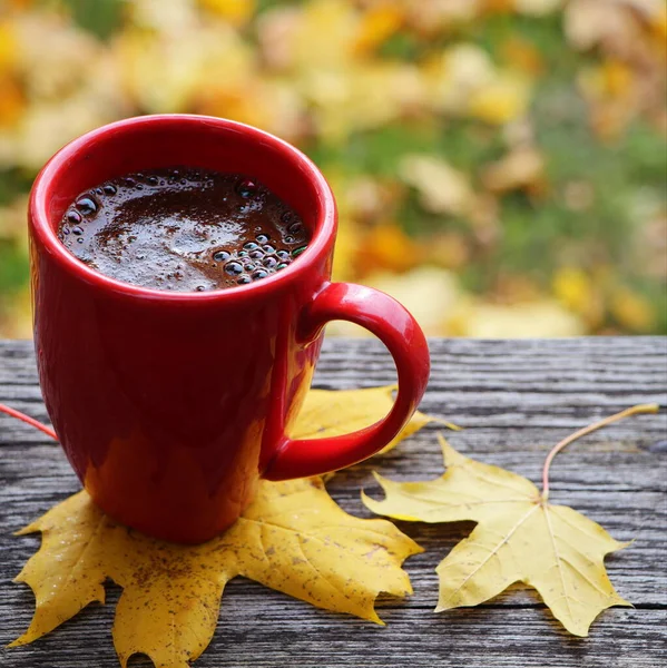 Autumn background. Blurred autumn leaves background with hot cup of coffee — Stock Photo, Image