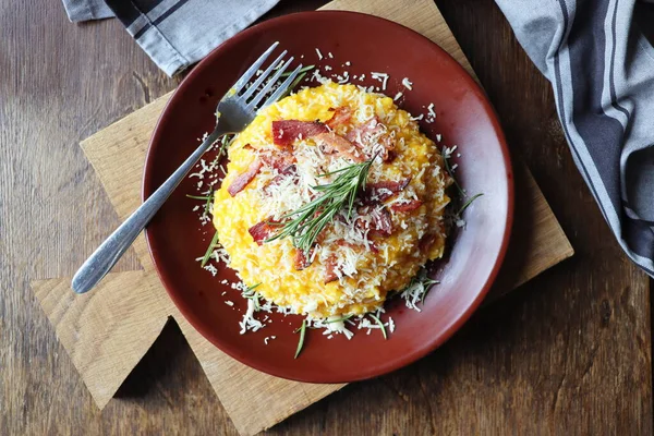Risotto with pumpkin and bacon on a dark wooden table. Top view — Stock Photo, Image