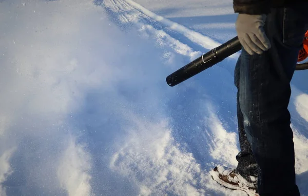 Människan rengör trottoaren från snö med fläkt Stockfoto