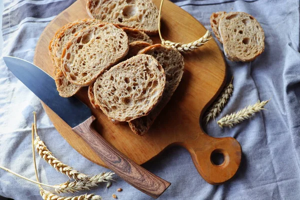 Čerstvě upečený žitný chléb na dřevěné řezací desce se zrny, plochý ležel — Stock fotografie