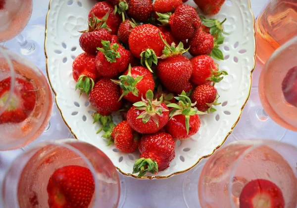 Rose wine glasses and delicious fresh strawberries on the white background, top view — ストック写真