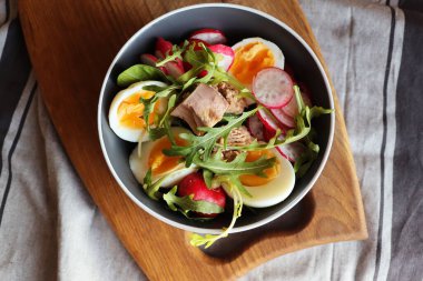 Taze salata. Ton balığı, turp, yumurta. Gri arka plan manzaralı roka. Sağlıklı yiyecekler. Bahar salatası