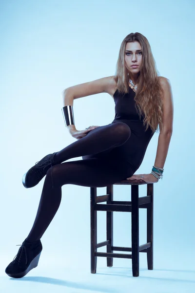 Junge blonde Frau im schwarzen Badeanzug sitzt auf Stuhl posiert Stockbild