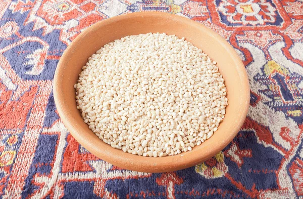 Obiloviny pšenice v misce hlíny nad Arménské koberec — Stock fotografie