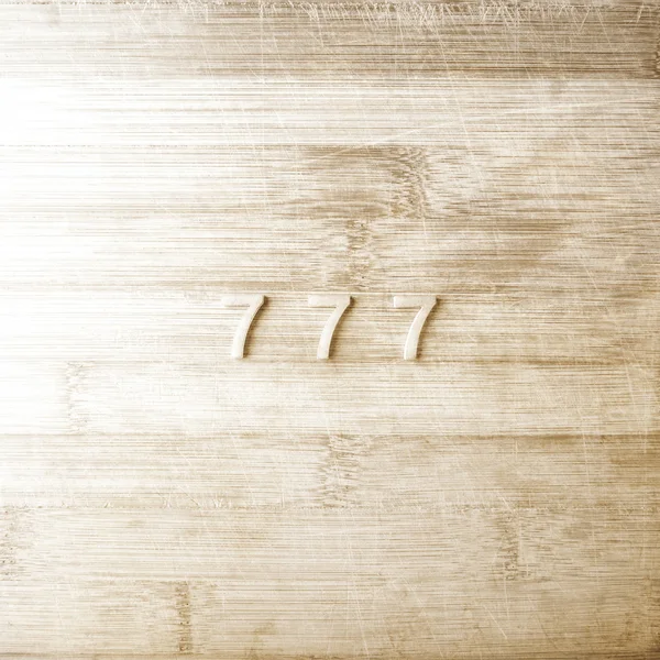 Three sevens on a wooden background — Stock Photo, Image