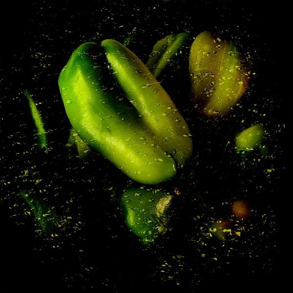 Pimienta verde sobre superficie húmeda brillante con gotas de agua y salpicaduras en el fondo original con reflejo — Foto de Stock