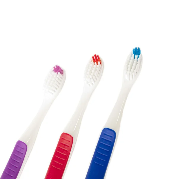 Three toothbrushes of different colors isolated over white background — Stock Photo, Image