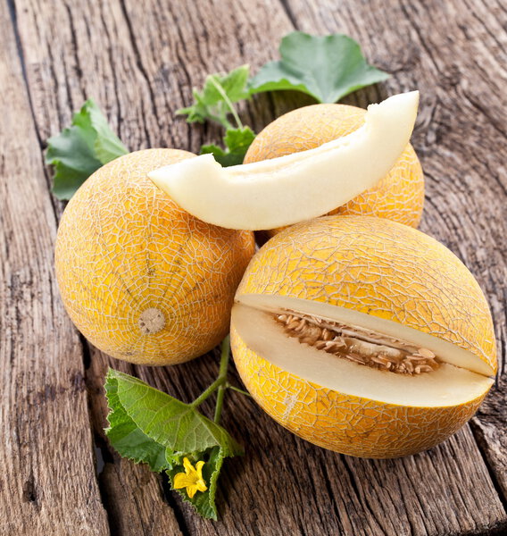Melon with slices and leaves on a old wooden table.