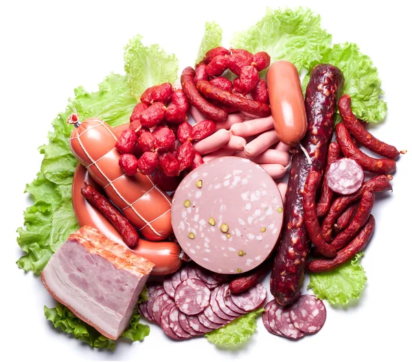 Meat and sausages on lettuce leaves. — Stock Photo, Image