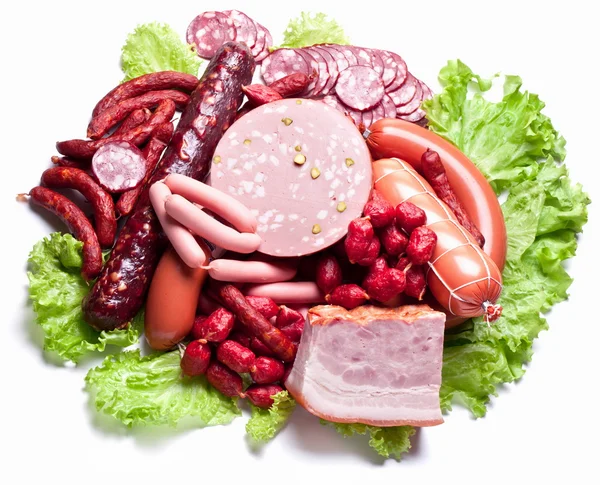 Meat and sausages on lettuce leaves. — Stock Photo, Image