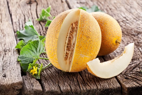 Melón con rodajas y hojas sobre una vieja mesa de madera . —  Fotos de Stock