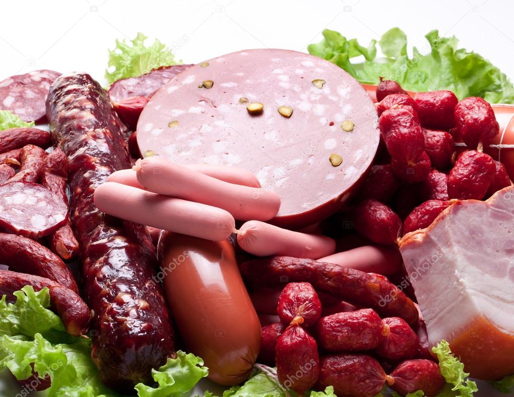 Meat and sausages on lettuce leaves.