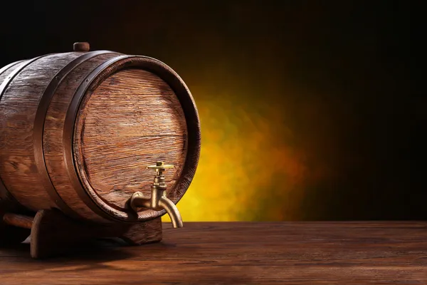 Barril de carvalho velho em uma mesa de madeira. Atrás do fundo escuro embaçado — Fotografia de Stock