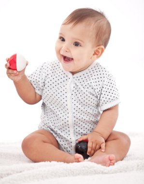 Happy 7-monthes baby girl playing with balls. clipart