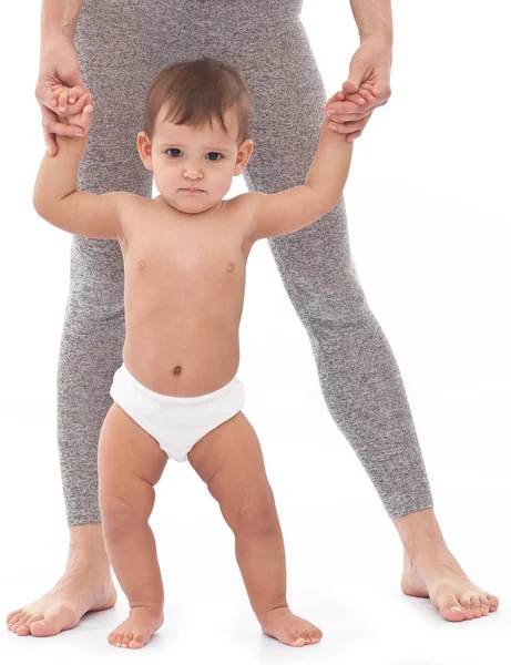 Bebé tratando de dar los primeros pasos con la ayuda de la madre . — Foto de Stock