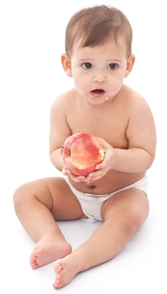 Bebê engraçado com maçã sentada no chão . — Fotografia de Stock