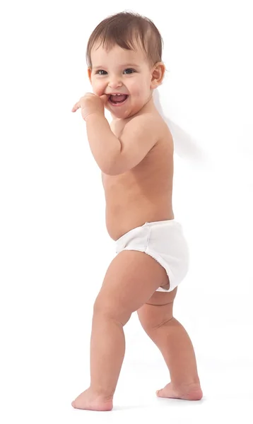 Bebé sonriente se queda cerca de la pared y sostiene el dedo en una boca . — Foto de Stock