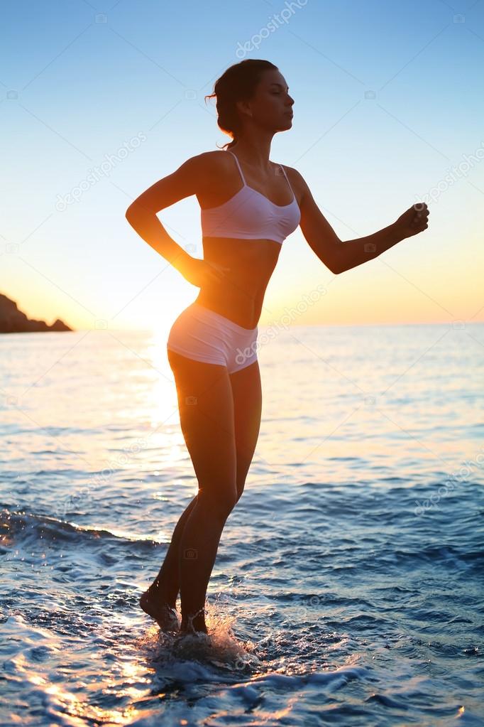 Sexy athletic woman running on the beach.