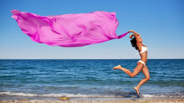 Sexy brune sportive sautant sur la plage . — Photo
