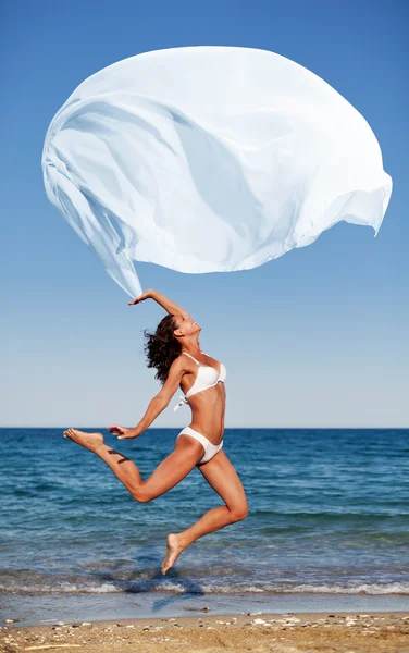 Sexy athletische Brünette springen auf dem Strand. — Stockfoto