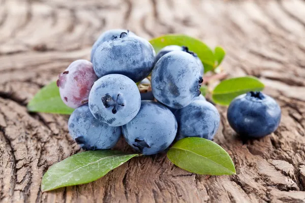 Blueberries with leaves on a wooden table. — Stock Photo, Image