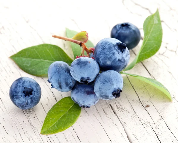 Bosbessen met bladeren op een houten tafel. — Stockfoto