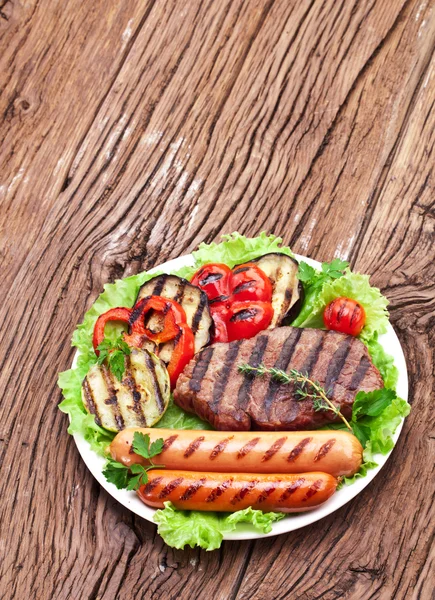 Steak vom Grill, Würstchen und Gemüse. — Stockfoto