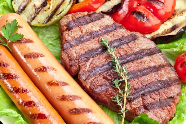 Gegrilde steak, worstjes en groenten. — Stockfoto