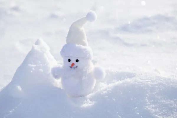 Pequeno boneco de neve engraçado perto do banco de neve . — Fotografia de Stock