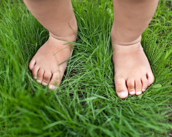 Liten söt baby fötter på gräset. — Stockfoto